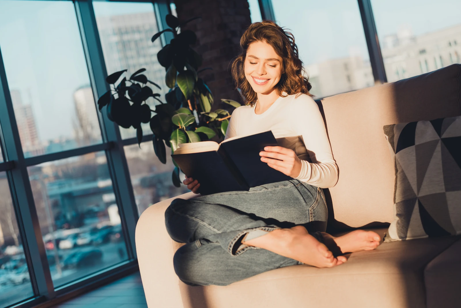 Woman reading a book at home in warm sunlight